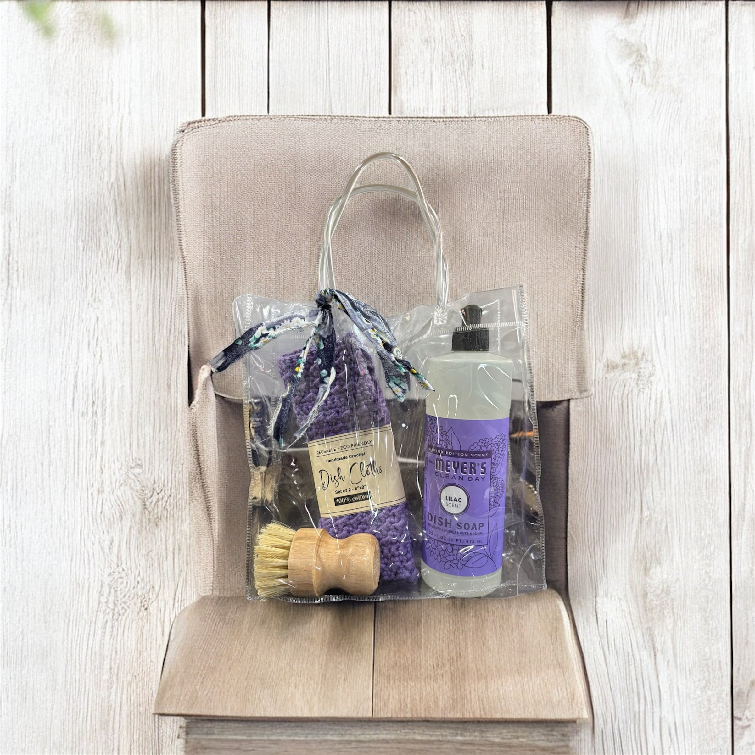 Cleaning supplies including a bottle, brush, and cloths in a clear bag on a wooden surface.
